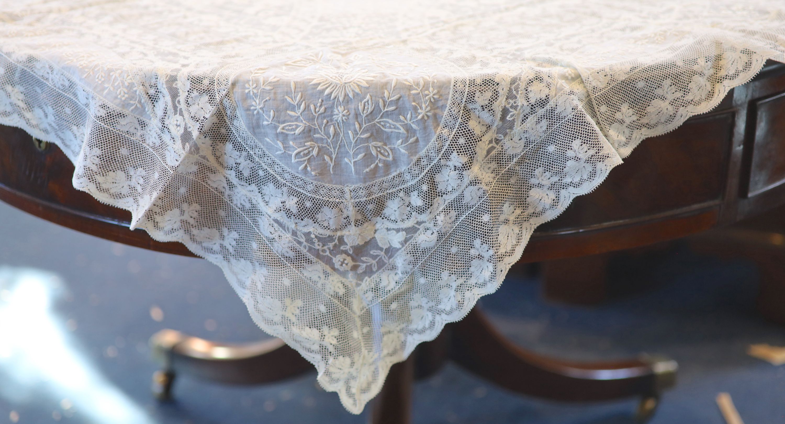 A square Normandy lace table cloth and approximately nineteen circular place mats and a centrepiece,